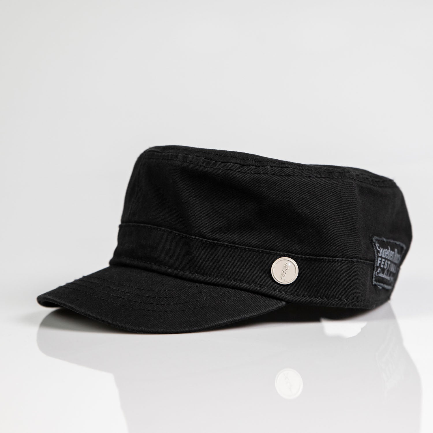 Army-kepsen är en svart keps i militär stil med platt topp, silverfärgad sidoknapp och kort skärm, tillverkad av bomull. Den visas på en vit reflekterande yta och är en del av det klassiska Sweden Rock-mode.