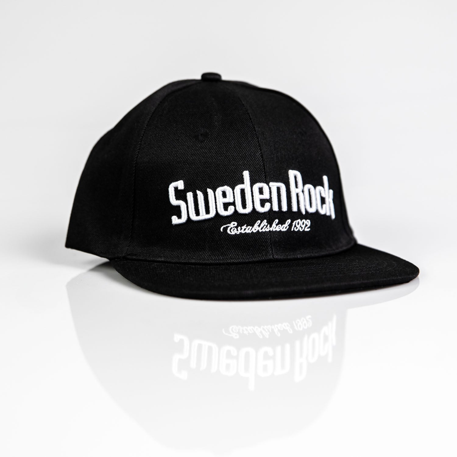 En Keps Classic svart snapback keps med rak skärm och vit broderad text "Sweden Rock Established 1992", visad på en vit reflekterande yta.