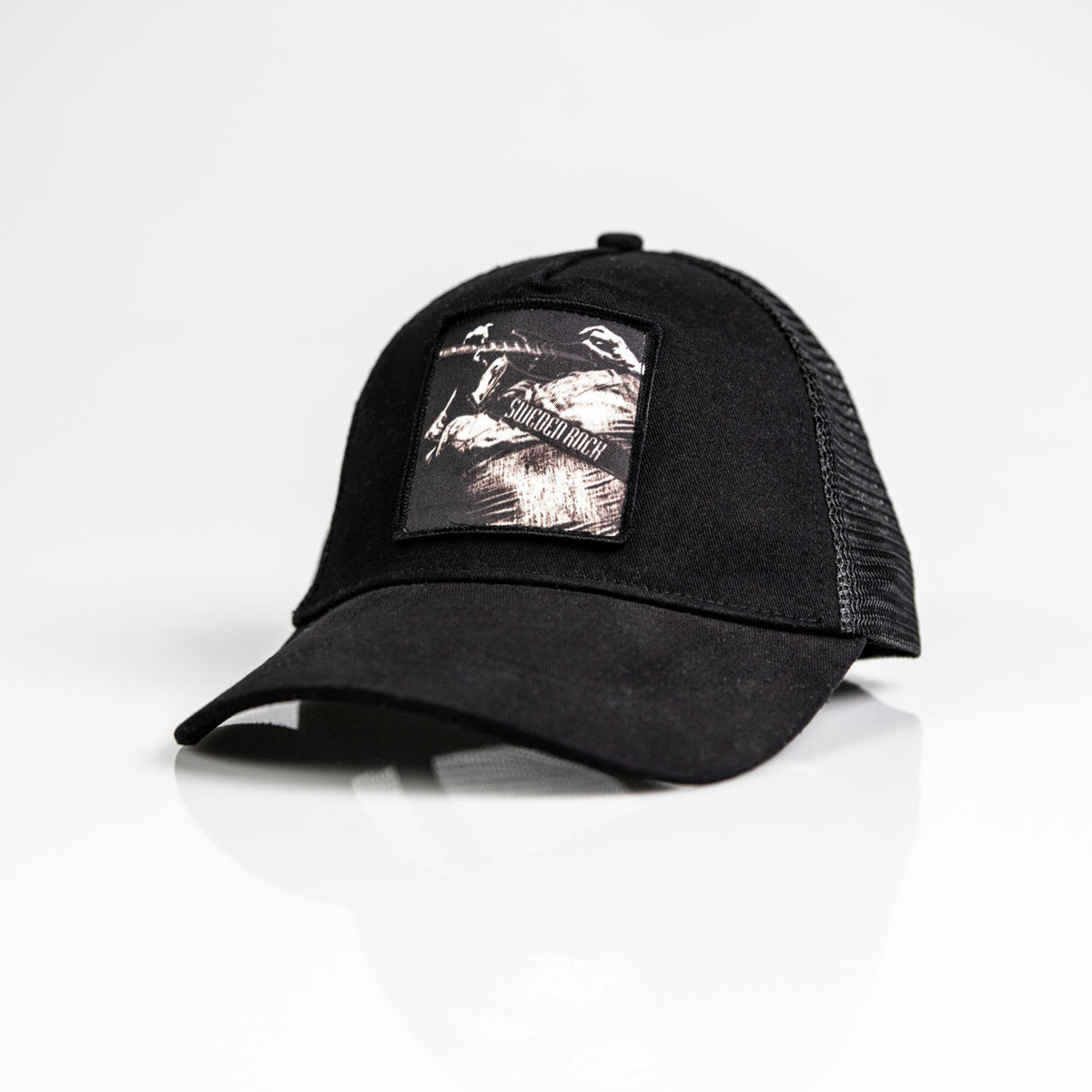 Keps Guitar Player är en svart truckerkeps med böjd skärm och mesh-baksida, med en rektangulär patch på framsidan med en gråskalebild av en elgitarrist. Denna snygga snapback visas på en vit yta.