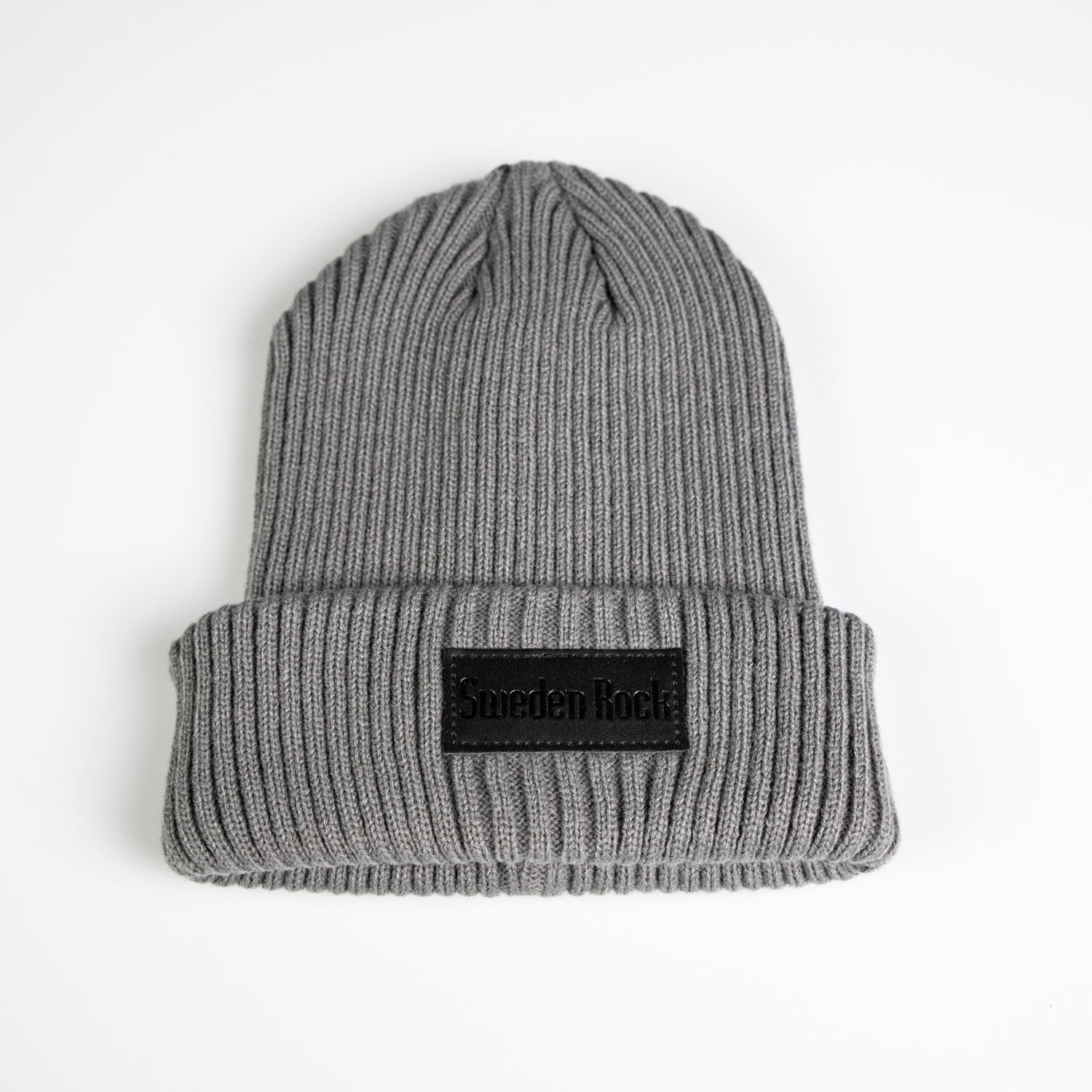 Beanie är en grå ribbstickad mössa i mjuk akryl med uppvikt brätte och en svart rektangulär Sweden Rock patch på vit bakgrund.