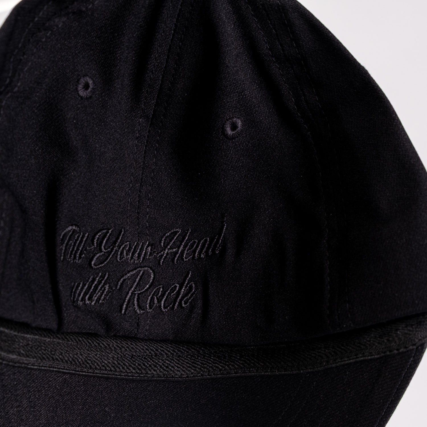 En närbild av Keps Flexfit Black on Black, med böjd skärm, svart broderad "Fill Your Head with Rock" på sidan, synliga sömmar och två ventilationsöglor.