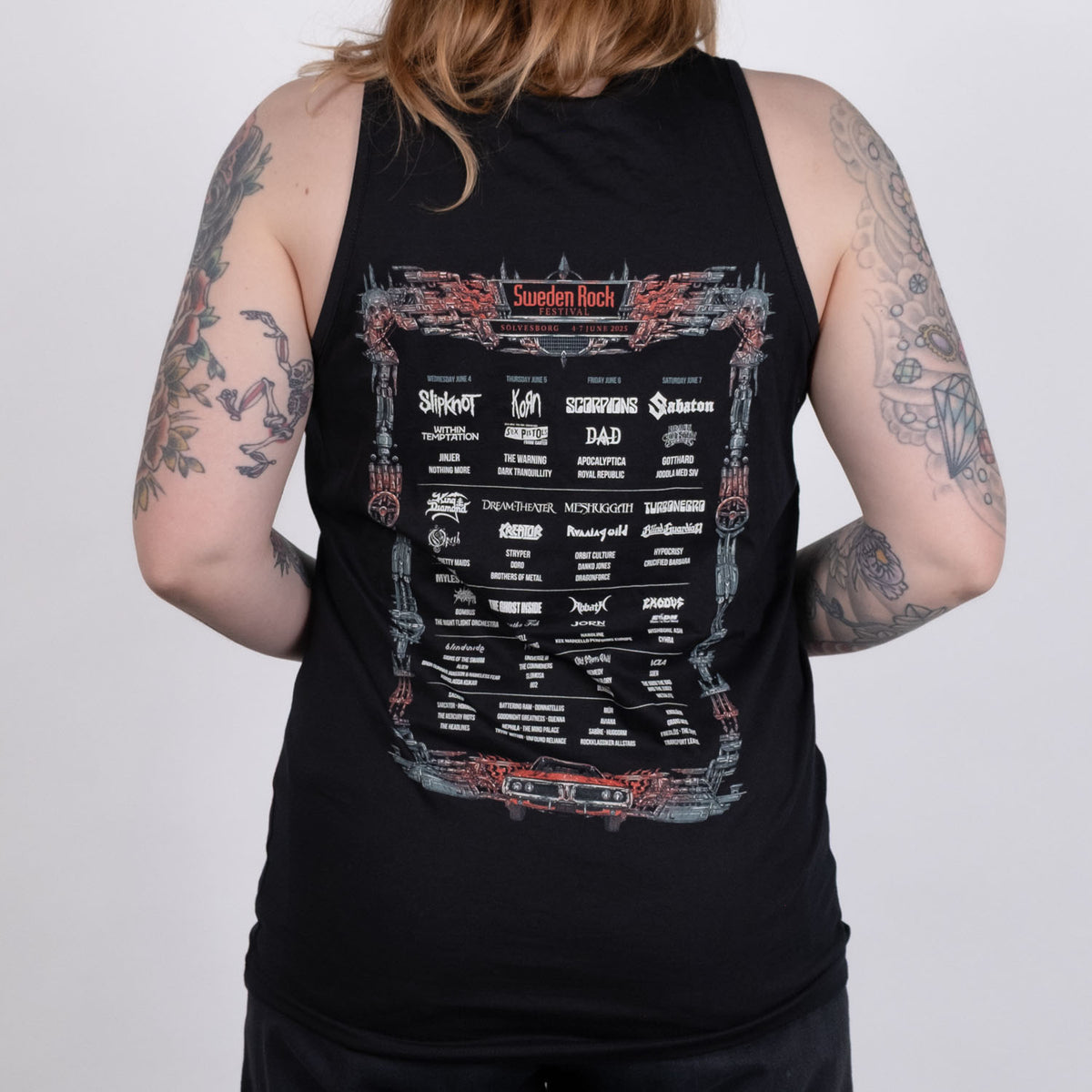 En tatuerad person vänder sig bort från kameran och bär Festival Tank Top i svart ekologisk bomull med ett tryck av Sweden Rock Festival 2023 lineup, med Slipknot, Pantera och Motley Crue.