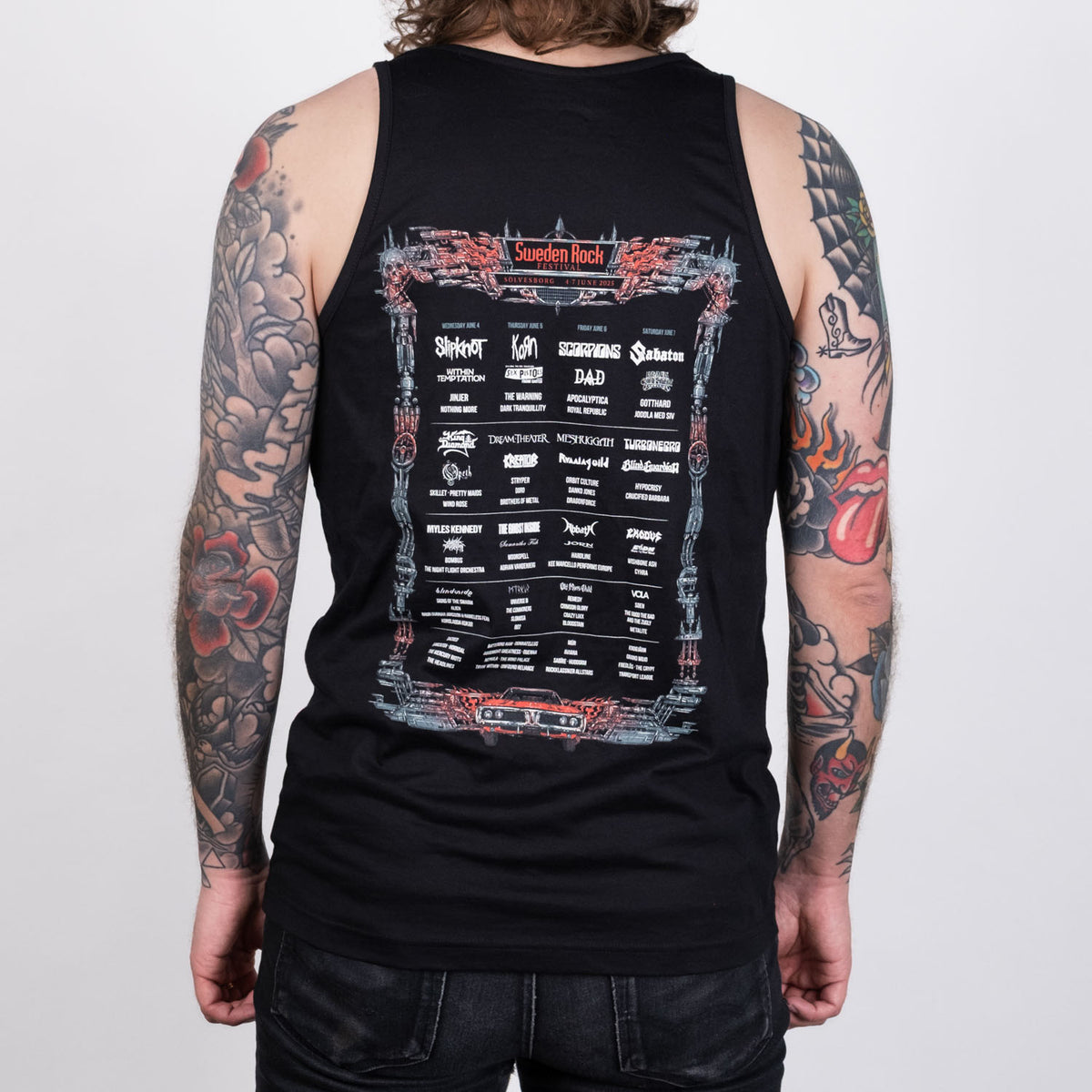 En tatuerad person ses bakifrån iklädd Festival Tank Top - svart, 100% bomull - med vittryckta bandnamn och Sweden Rock festivaldetaljer på ryggen.