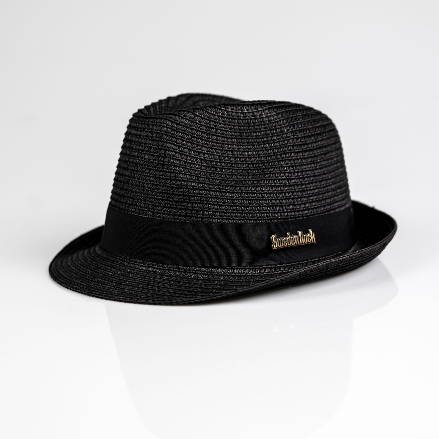Stråhatt Svart är en svart vävd fedora med svart band och en "Suicidal Tendencies"-pin i guld, finns i tre storlekar och visas på en vit bakgrund.