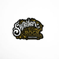 Klistermärke Festival Cursive är ett dekorativt klistermärke med utsmyckade bokstäver i guld och vitt med texten "Sweden Rock Festival" på en svart bakgrund, mot en vit yta.