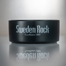 Skål - en svart keramikskål med texten "Sweden Rock Established 1992" i silver på sidan, visad mot ljus bakgrund med spegling under.